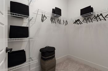 A white closet with clothes hanging and shelves.